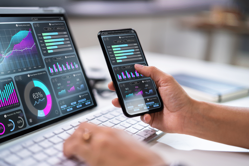 Pantalla de laptop y teléfono mostrando paneles de datos y métricas de marketing digital.
