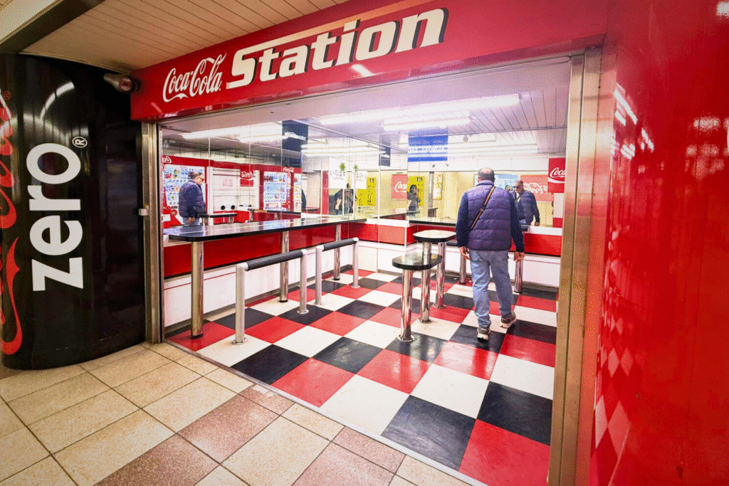 Espacio temático de Coca-Cola Station en la estación del metro de Tokyo, con colores rojos y elementos de marca.