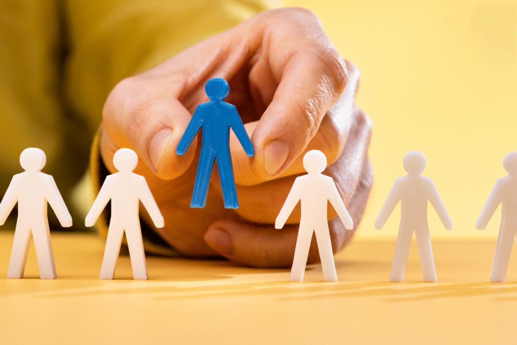 Mano seleccionando una figura azul entre figuras blancas sobre fondo amarillo.